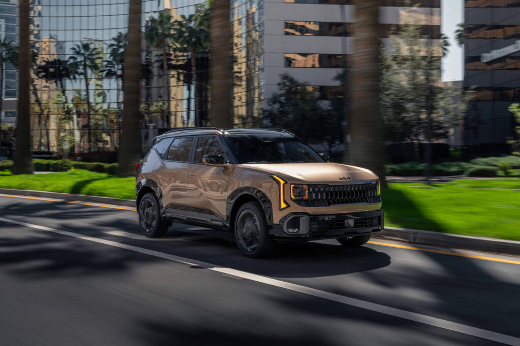 2027 Kia Seltos X-Line in bronze driving past palm trees and glass office towers