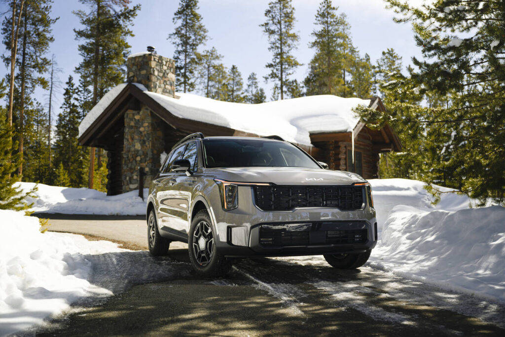 2027 Kia Sorento parked outside a snow-covered log cabin