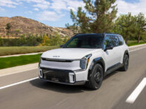 2027 Kia EV9 driving past rolling hills