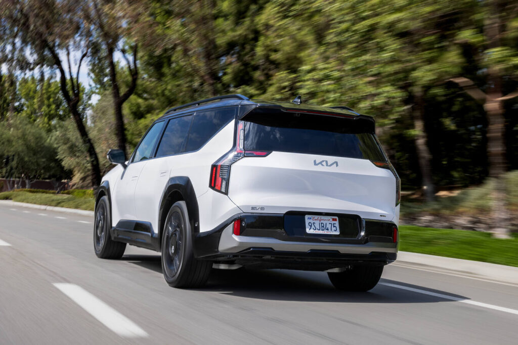 2027 Kia EV9 from behind on a tree-lined road