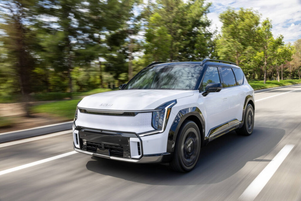 2027 Kia EV9 driving on a tree-lined road