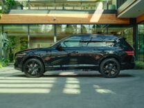 2027 Genesis GV80 Prestige Black in profile outside a glass building